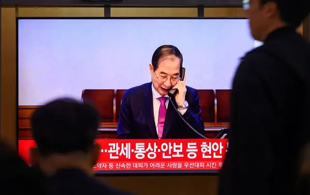 통화하는 한덕수 모습을 담은 뉴스 화면을 보고 있는 사람들