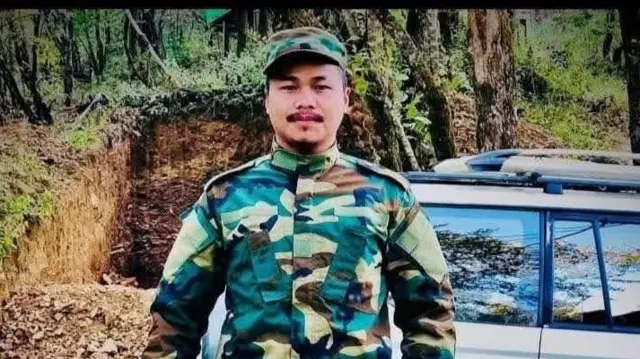 ကားတစ်စီးဘေးမှာ စစ်ဝတ်စုံဝတ်ပြီး မတ်တပ်ရပ်နေတဲ့ ဆလိုင်းဆန်လင်း