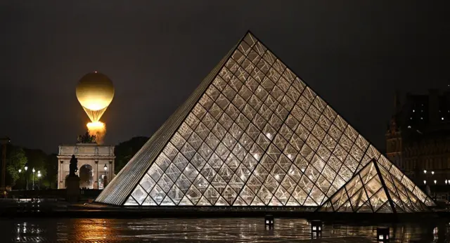 La vasque, avec la flamme olympique allumée, s'envole attachée à un ballon, à côté du Louvre, lors de la cérémonie d'ouverture des Jeux olympiques de Paris 2024, à Paris, le 26 juillet 2024.