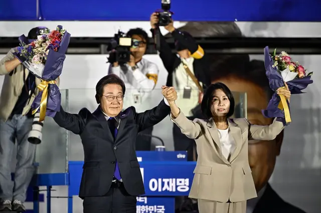 당선이 확실시된 이재명 더불어민주당 대통령 후보가 김혜경 여사와 4일 오전 서울 여의도 국회 앞을 찾아 꽃다발을 들어보이고 있다