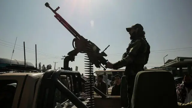 یک سرباز طالبان که پشت یک ماشین دارد بالای یک موتر رنجر قرار دارد.