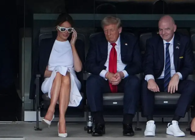 Trump oturuyor, pantolonunun paçası kıvrılmış ve ayağındaki şişiklik görünüyor.