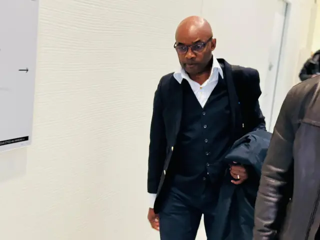 Charles Onana arimo agenda mu nzu, afise ikote mu ntoke, ahetse n'igikapu ku rutugu