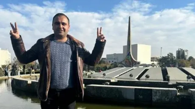 دکتر شاروان ایبش دو دستش را به علامت پیروزی بالا برده 