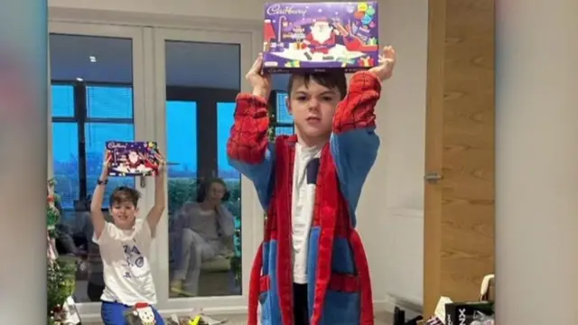 Karen, derrière une vitre , regarde ses enfants avec leurs cadeaux de Noël