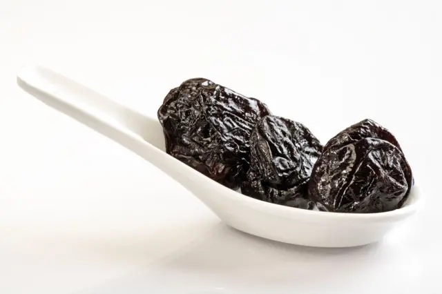 فواكه مجففة لونها أسود في طبق أبيض.