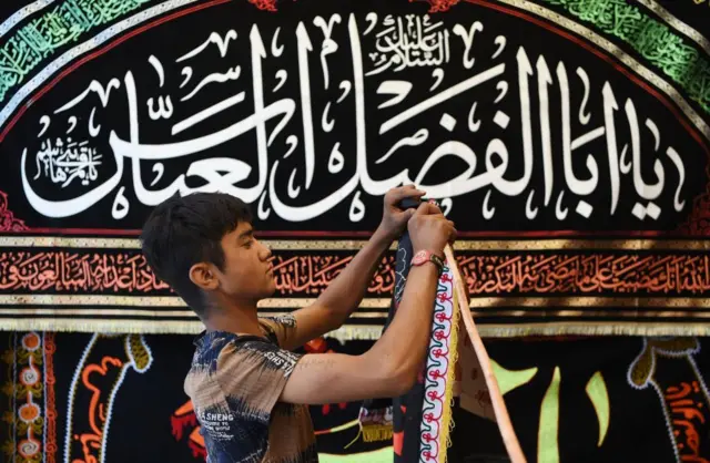 In this photograph taken on September 25, 2017, an Afghan young Shiite boy displays religious flags ahead of Ashura along a roadside in Kabul.