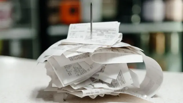 Notas fiscais empilhadas, após serem perfuradas em espeto de metal