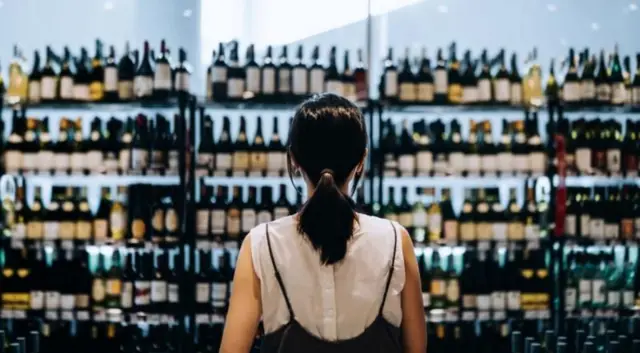 Mulher olha prateleiras de bebidas em estabelecimento