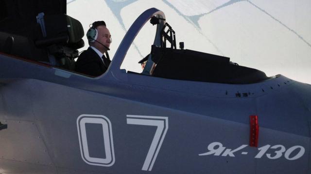 Vladimir Putin operates a flight simulator during a visit to a military facility this month - the war in Ukraine is ever-present in life in Russia