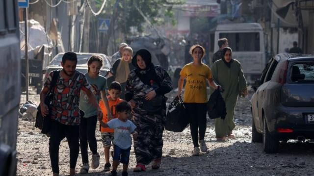 Mujeres y niños evacúan una zona bombardeada del norte de Gaza, 11 de octubre 2023