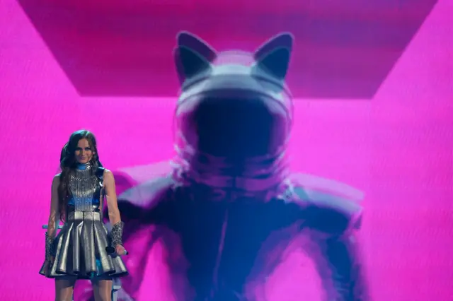 Devojska u srebrnoj kratkoj haljini na sceni sa dugom crnom kosom