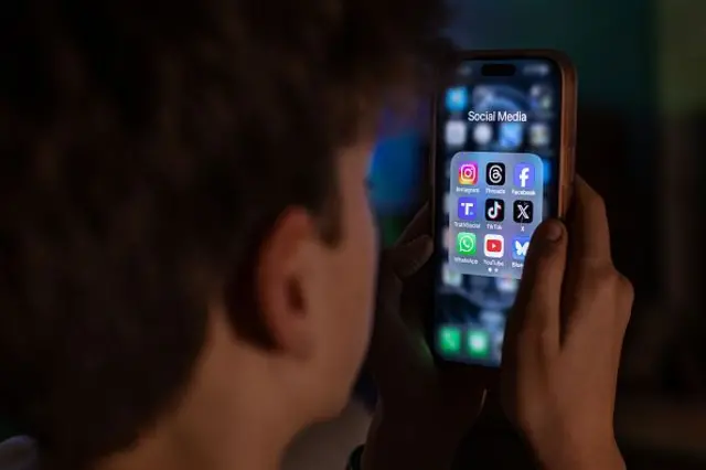 Підліток дивиться у смартфон із соцмережами на екрані