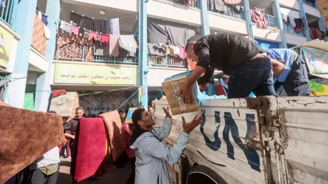 UN workers and volunteers unload aid from a truck in Khan Yunis