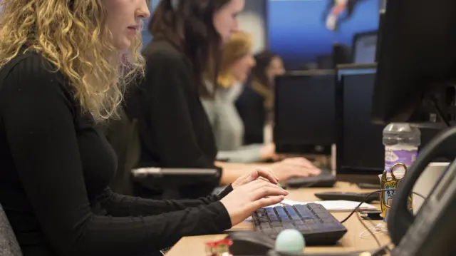 девојка са плавом косом у црном џемперу седи за комјутером