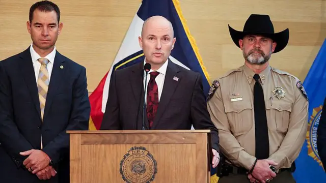 El gobernador de Utah habla en rueda de prensa acompañado de un agente de la oficina del sheriff y otro hombre con traje y corbata