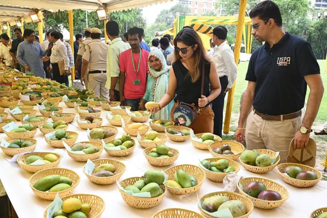 Les gens regardent des mangues lors d'un festival de mangues avec différentes variétés de fruits sur une table en Inde.