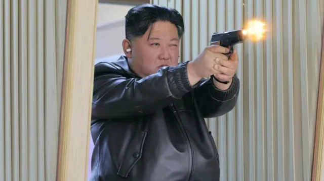 حاكم كوريا الشمالية كيم جونغ أون يرتدي بزة جلدية سوداء ويطلق النار من مسدس ويضع سدادات في أذنه