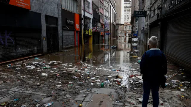 Pessoa observa rua destruída e águaapostas online da foxinundação abaixando