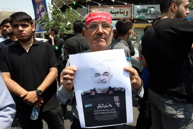 Протесты в Тегеране после израильского удара, один из протестующих держит в руках портрет Хоссейна Салами