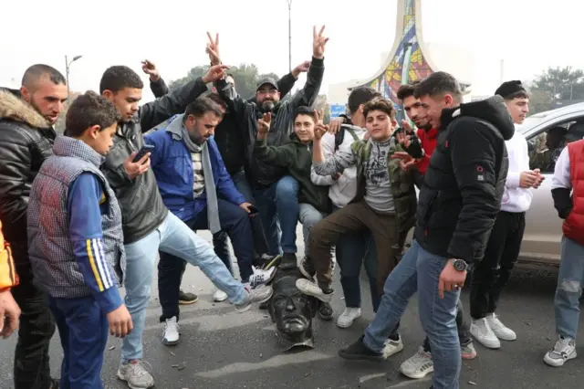 Un grupo de hombres celebran colocando sus pies sobre la cabeza de un busto de Hafez al Assad, padre de Bashar y fundador del caído régimen sirio.