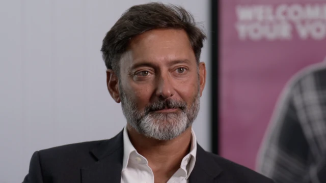 維賈伊·蘭加拉詹（Vijay Rangarajan）穿著白色襯衫，頂部紐結敞開，搭配黑色西裝外套。