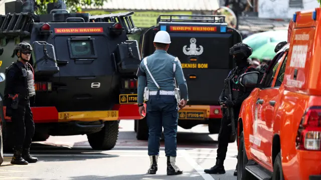 یک دژبان ارتش در میان ماشین‌های پلیس اندونزی بیرون از محل انفجار مدرسه دیده می‌شود