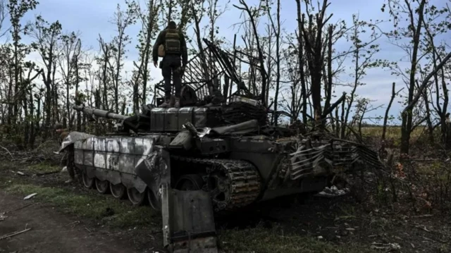 Изюмдун четинде ташталган орус танктын үстүндөгү украин жоокери