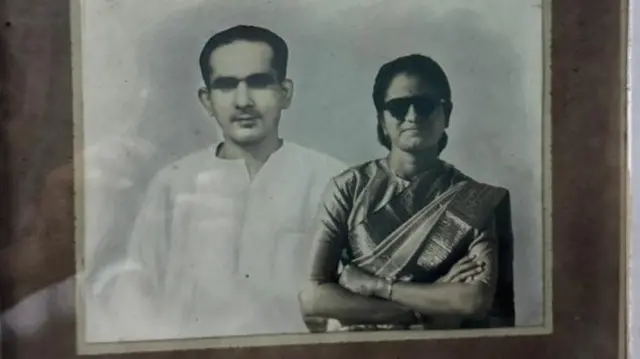 डॉक्टर के लक्ष्मीबाई और उनके पति डॉक्टर प्रकाश राव की एक पुरानी तस्वीर फ़्रेम में दीवार पर टंगी हुई