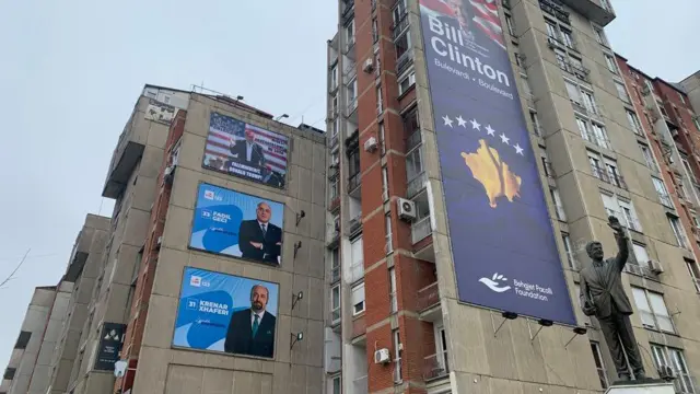 Dva predizborna postera iznad kojih je Donald Tramp, a na zgradi pored je bilbord posvećen Bilu Klintonu, bišvem američkom predsedniku, gde je postavljena i njegova statuta