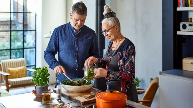 Duas pessoas de meia idade cozinhando