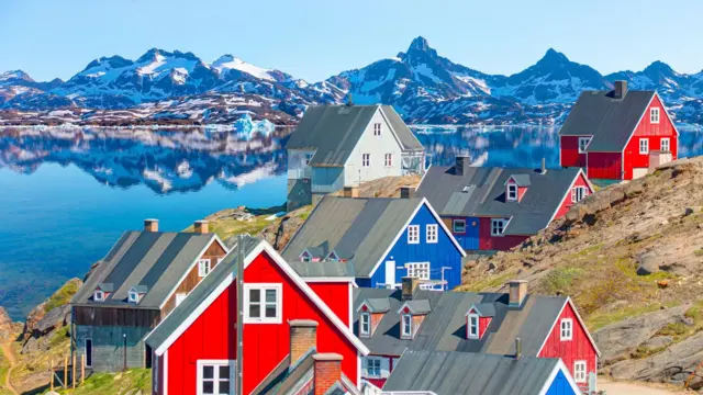 خانه‌های رنگی در کنار آب با پس منظر کوهستان نیمه برفی 