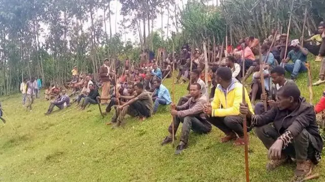 ባህላዊ የጦር መሳሪያዎችን ይዘው የተሰበሰቡ ሰዎች ቁጭ ብለው