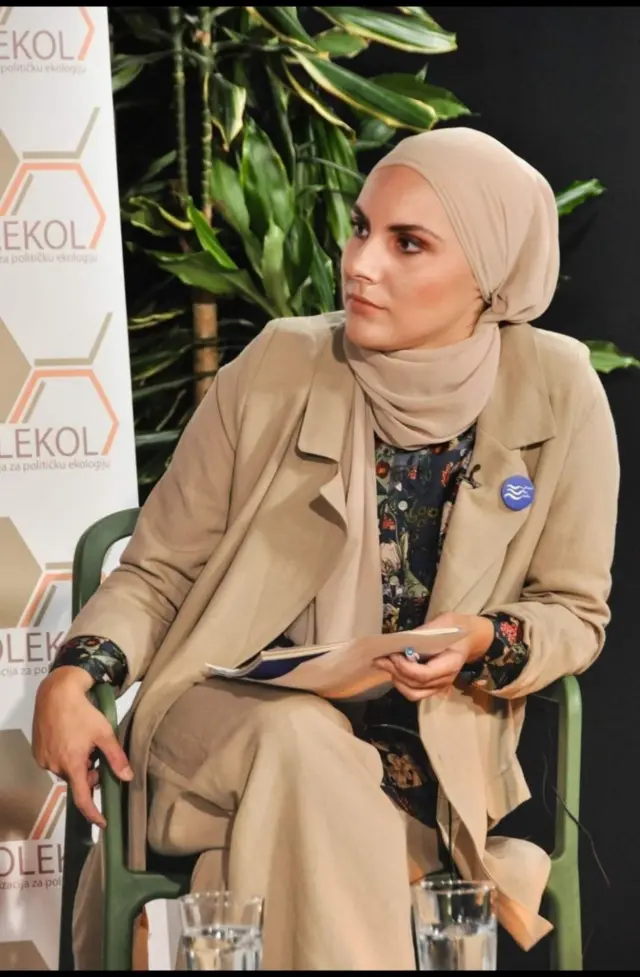 Devojka prekrivene glave sedi za govornicom