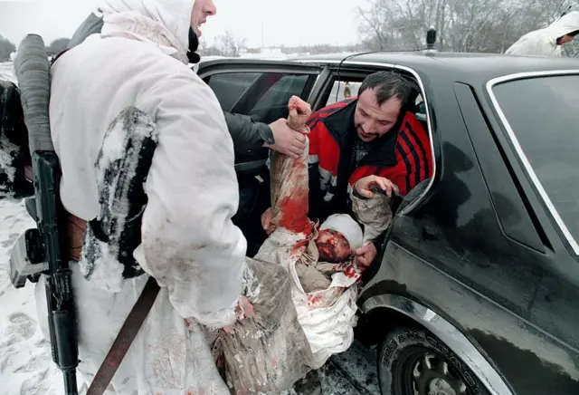 Раненого грузят в машину на окраине Грозного