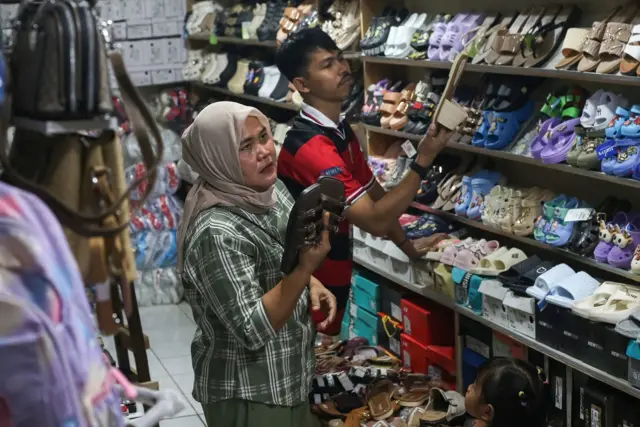 Seorang perempuan sedang memilah-milah alas kaki yang hendak dibeli.