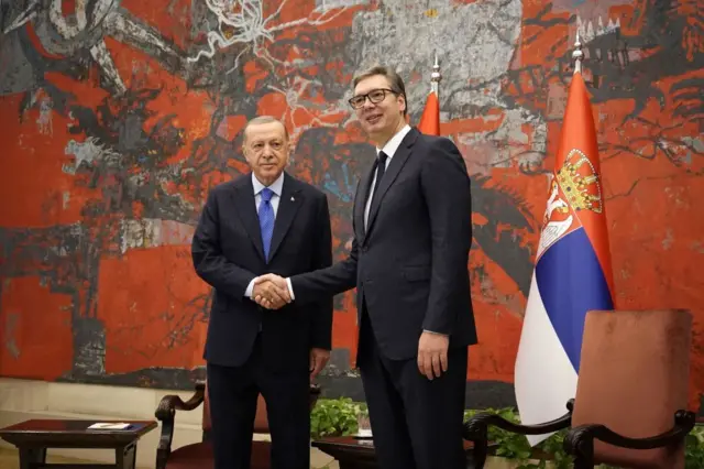 Erdoğan ve Vucic el sıkışıyor yanlarında Sırbistan bayrağı ve koltuklar var. 