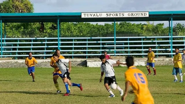 Des jeunes jouent au football sur un terrain de sport à Tuvalu.