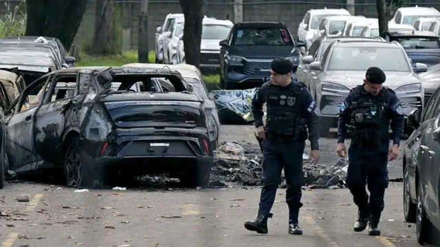 Policias analisam área de acidente em que helicóptero caiu sobre carros.
