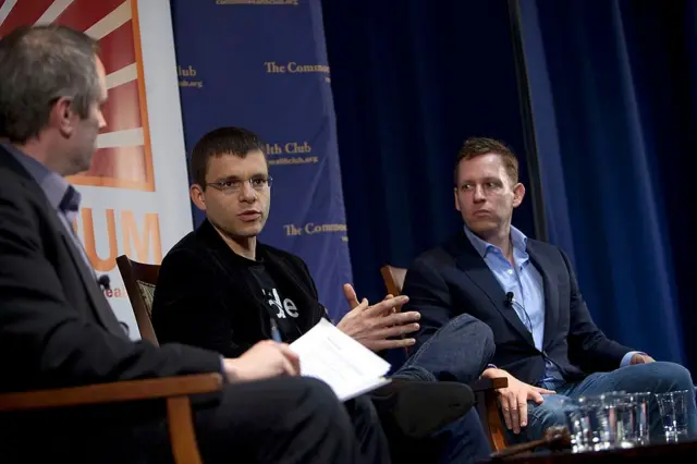 Max Levchin y Peter Thiel sentados, hablan en una conferencia de negocios.