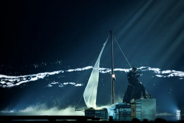 Muškarac na sceni u tamnom kožnom mantilu