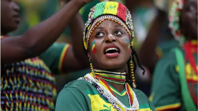 Fan wearing colours of the Senegal flag in a crowd of people watching the football.
