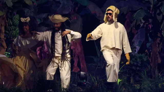 Bad Bunny junto a dos artistas que lo acompañan en el escenario.