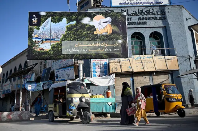 Una mujer con burka camina con su hija tomada de la mano por una calle de Kandahar.