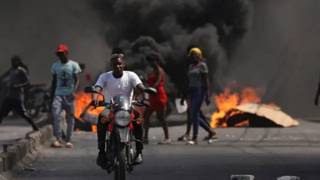 One man dey ride past burning barricade during a protest against Prime Minister Ariel Henry'goment 