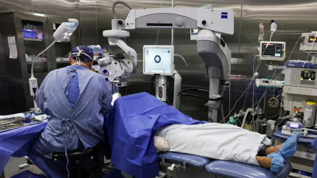 رجل يرقد على سرير في مستشفى وطبيب يجري له عملية جراحية.