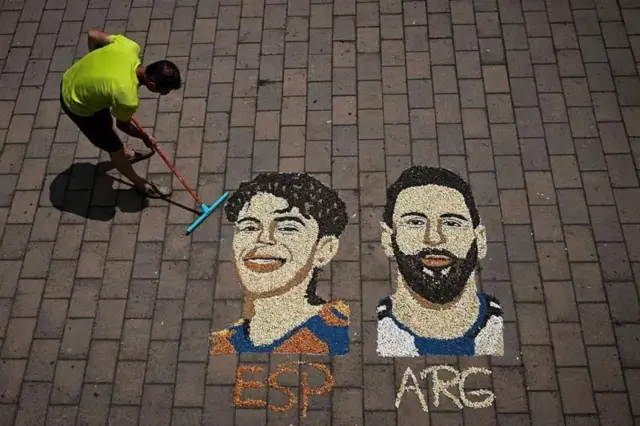 Arte com areia em uma rua com os rostos de Messi e Lamine