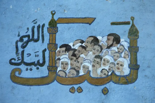 جدارية قديمة على أحد البيوت المصرية تمثل الحج إلى مكة المكرمة، رُسِم عليها وجوه كثيرة تمثل حجاجاً داخل كلمة "لبيك اللهم لبيك" واللام وحرف الكاف فيها على شكل مئذنة
