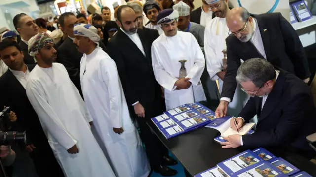 عباس عراقچی در حال امضا نسخه عربی کتاب خود در نمایشگاه کتاب مسقط 