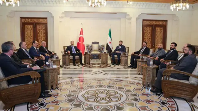 Türk heyetin Şam'daki Halk Sarayı'na ziyaretinden bir fotoğraf. Ortada Dışişleri Bakanı Hakan Fidan ve Suriye geçiş yönetimi Devlet Başkanı Ahmed eş-Şera oturuyor.